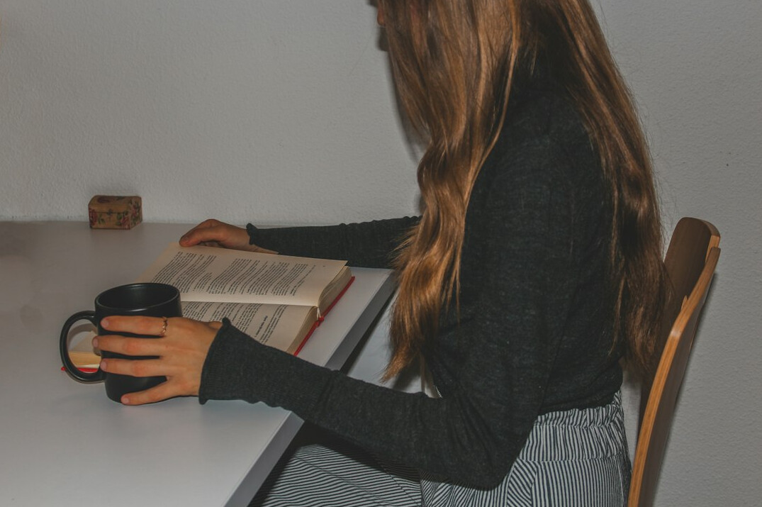 Writer typing at a desk surrounded by notes and a coffee cup